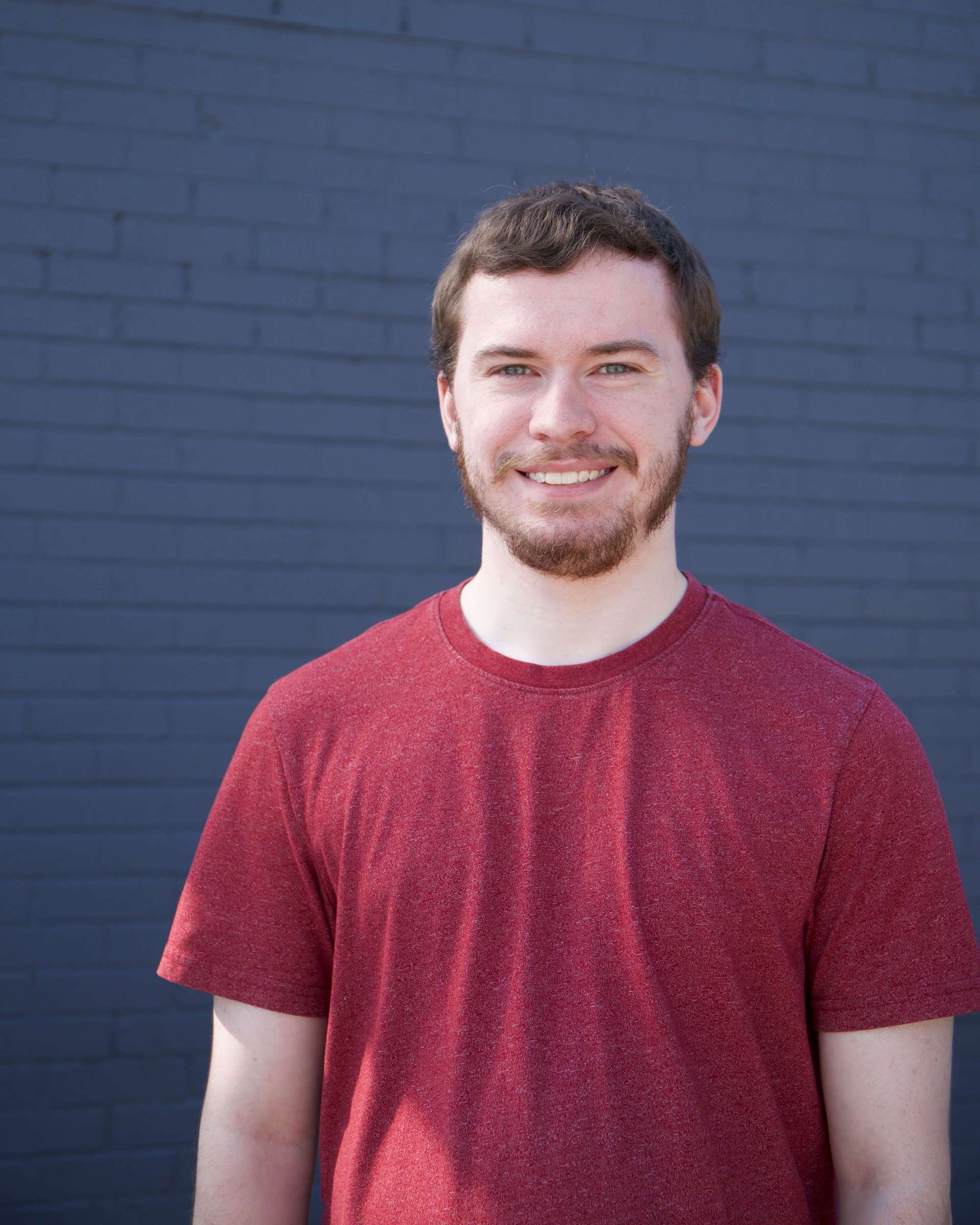 Picture of Ethan Matzdorf standing in front of a blue brick wall